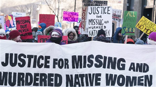 women holding sign that reads: justice for missing and murdered native women