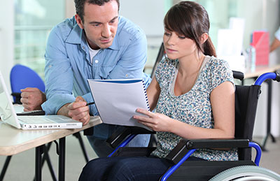 woman in a workplace in a wheelchair with a man