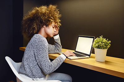 woman looking stressed out at laptop in home office